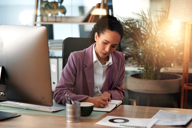 Computer, planning and writing with business woman at desk for investment or portfolio management. Agenda, finance and notebook with stock market broker in workplace for strategy development
