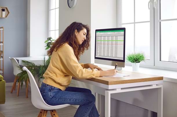 Female analyst working with spreadsheet data on a computer screen.