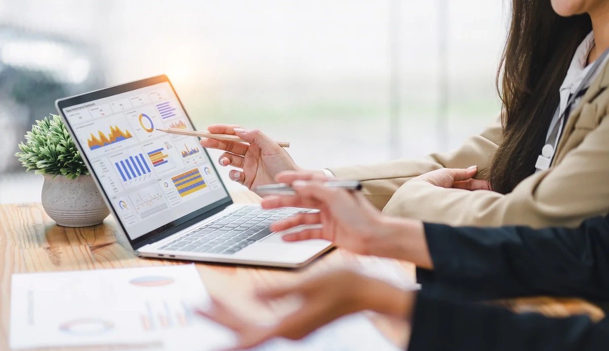 Hands pointing at laptop screen displaying Power BI dashboards and charts during Microsoft Power BI training