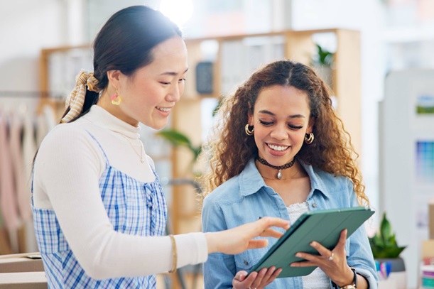 Woman, fashion designer and tablet in meeting, planning or logistics in small business together at office. Creative female person or employees working on technology for clothing design or startup.