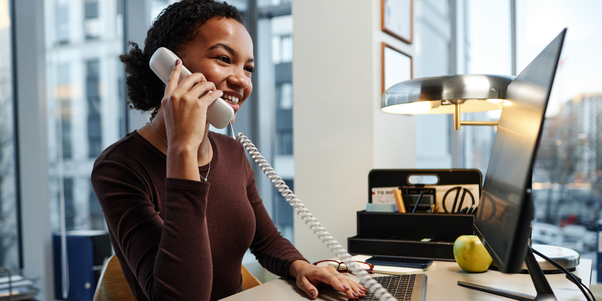 Close-up of a cheerful legal secretary in Cork speaking with a client over the phone, emphasizing the interpersonal and communication skills needed in a legal secretarial role.