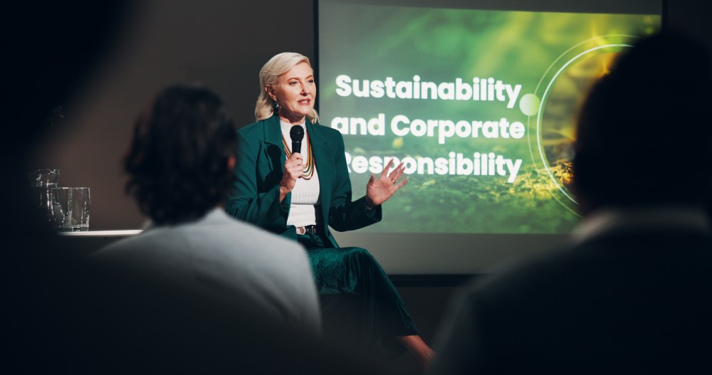 Professional woman presenting on sustainability and corporate responsibility at a business seminar, representing Pitman Training’s Sustainability in Business Award programme.