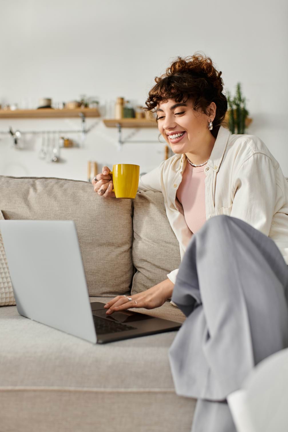 Smiling student on a sofa with a laptop and coffee, showing how Pitman Training Wexford offers flexible learning that fits around work and family commitments.