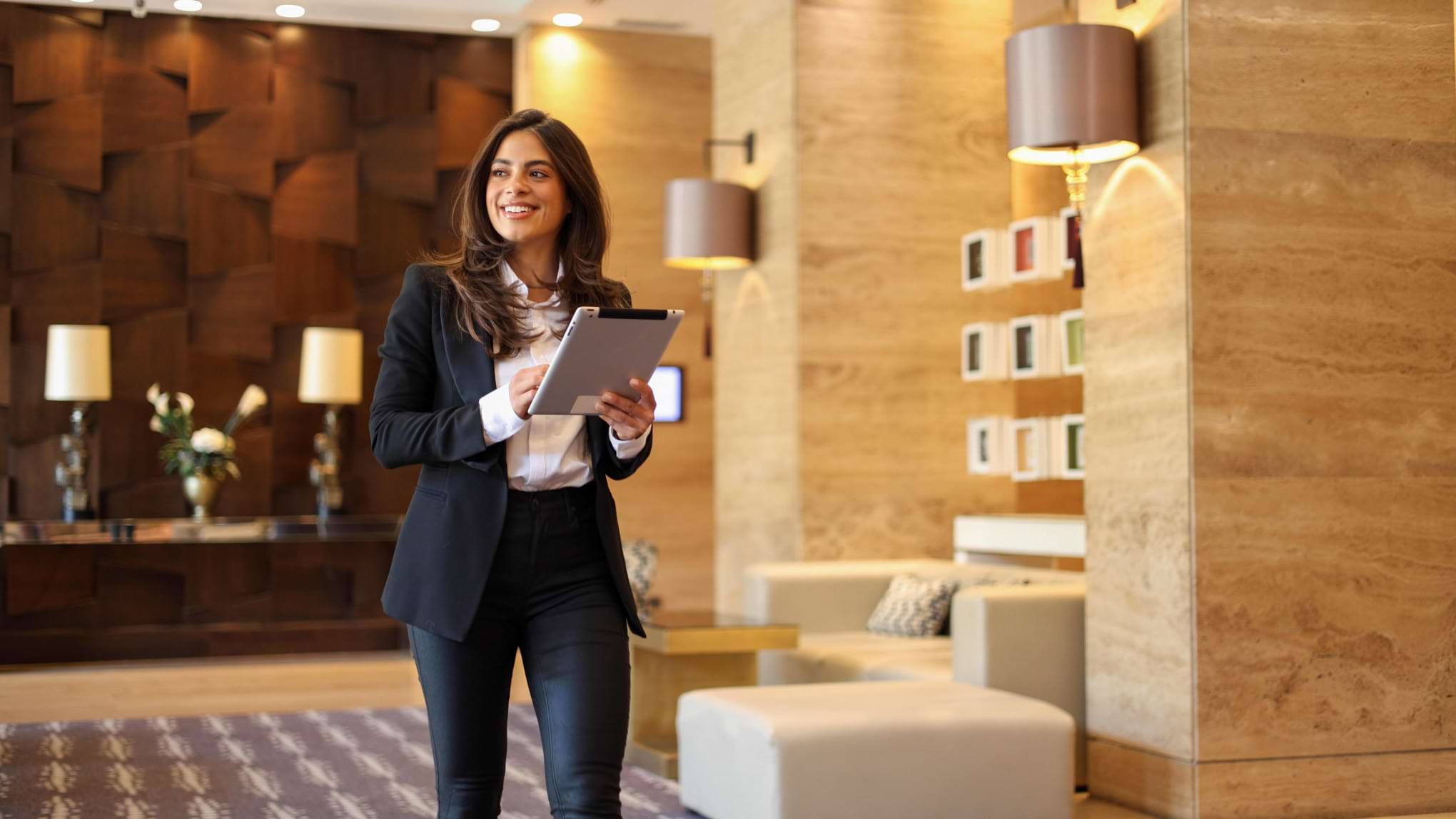 Professional hospitality staff member holding a tablet in a modern hotel reception area